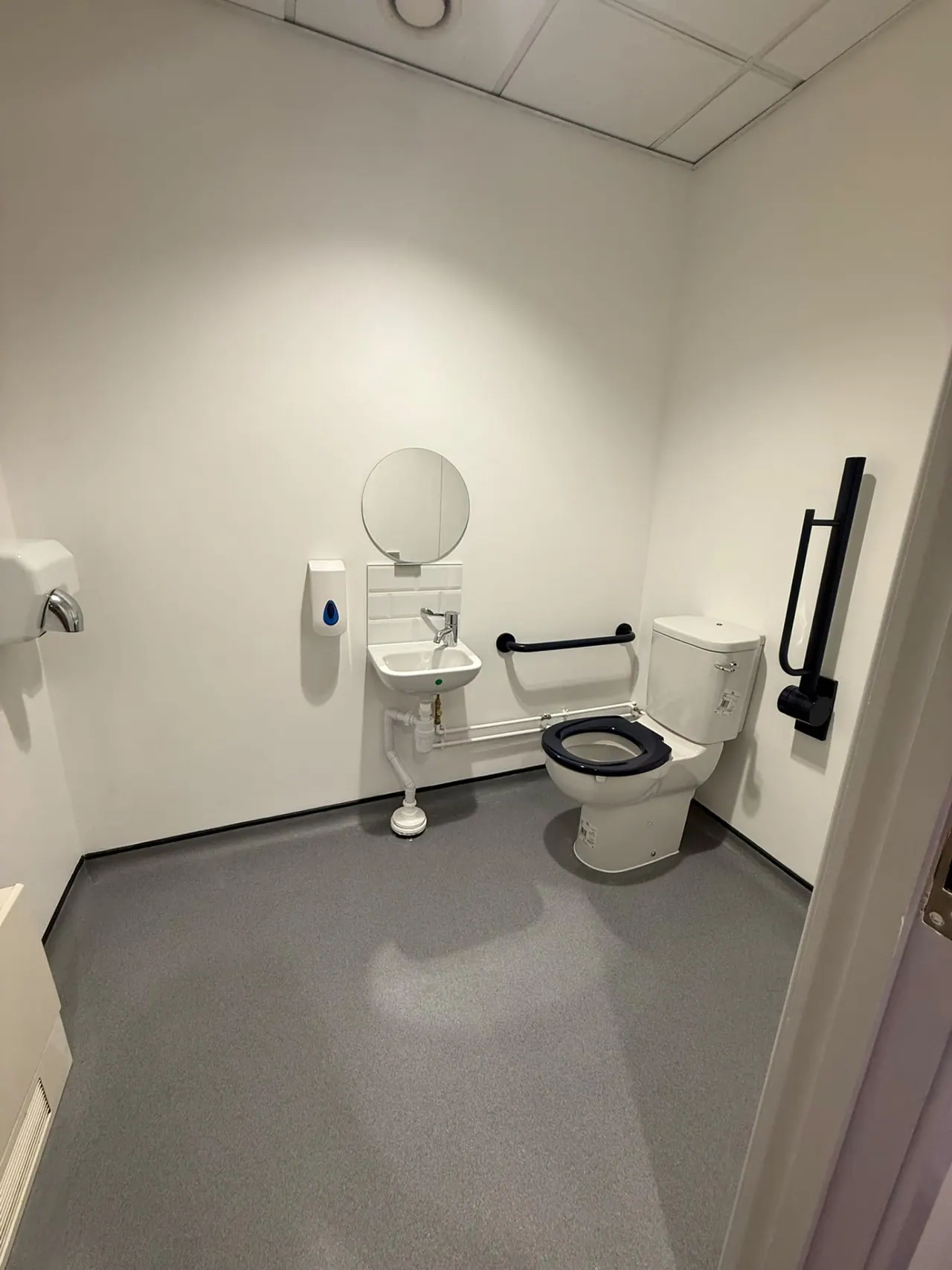 Refurbished commercial washroom with accessible toilet, grab rails and basins in Essex