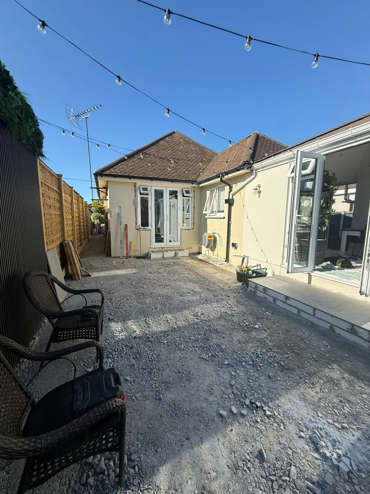 Garden before patio and fencing work, with old slabs and bare ground