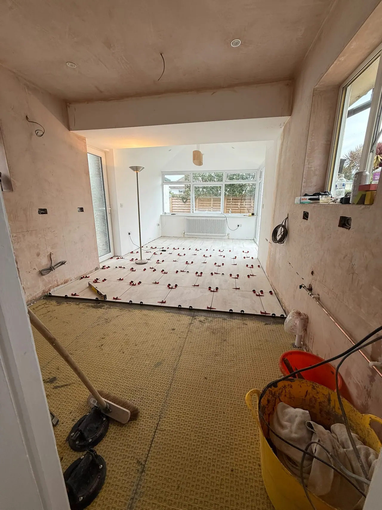 Floor tiling in progress with levelling clips on a room renovation in Essex