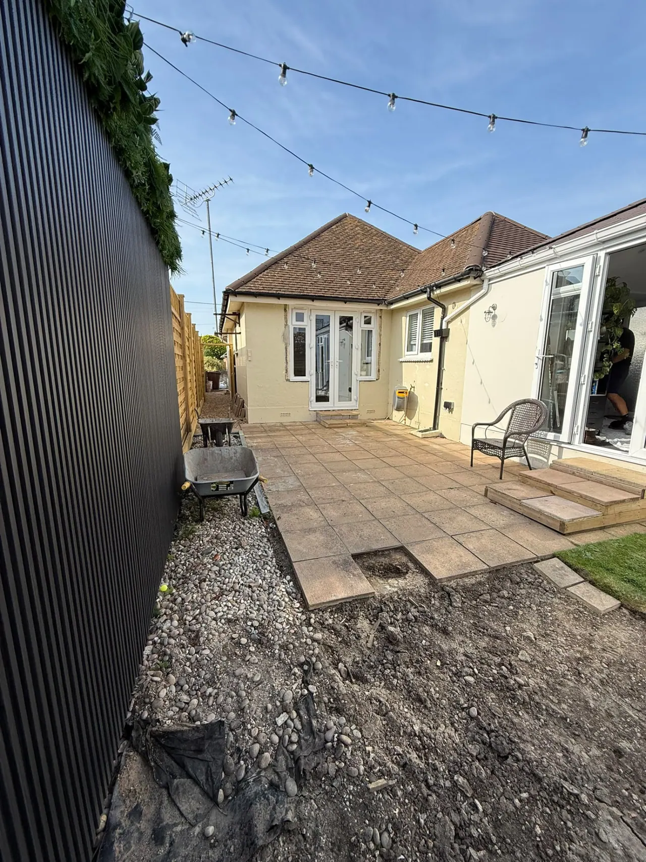 Garden before patio and fencing work, with old slabs and bare ground