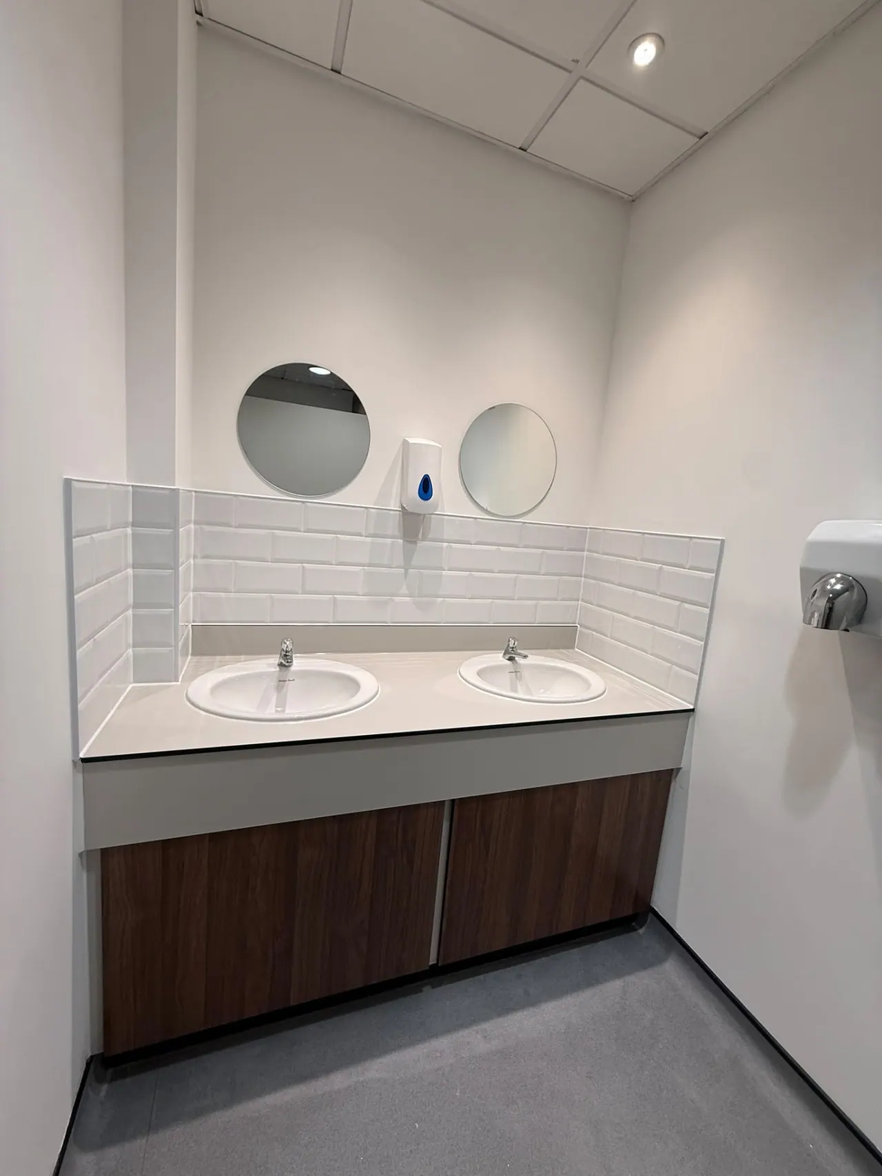 Refurbished commercial washroom with accessible toilet, grab rails and basins in Essex