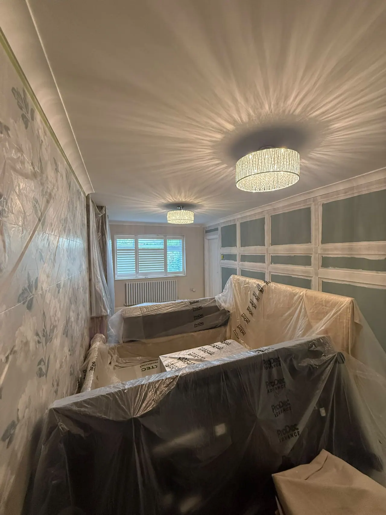 Room during painting and decorating preparation, furniture protected and panelling being fitted