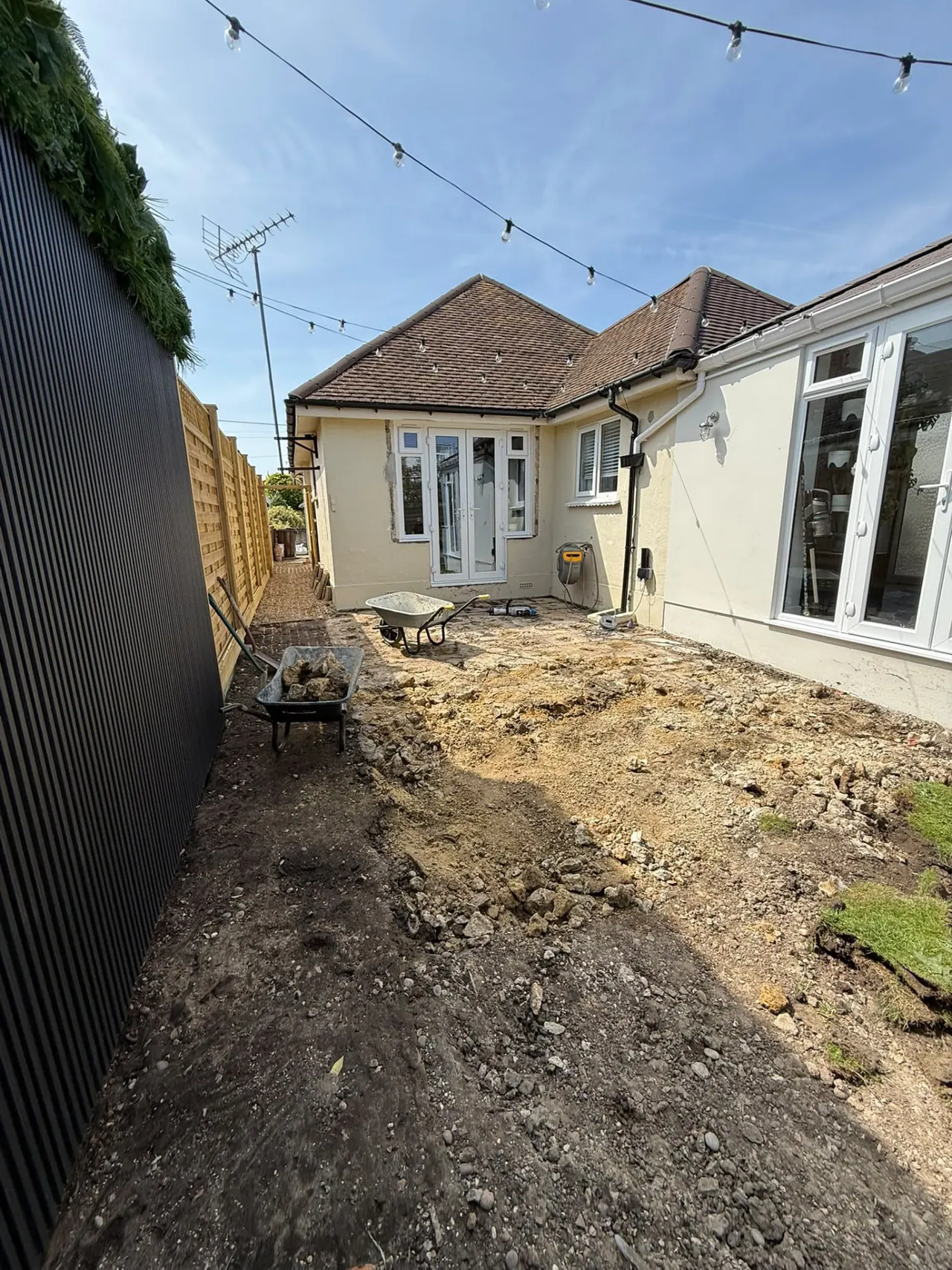 Garden before patio and fencing work, with old slabs and bare ground