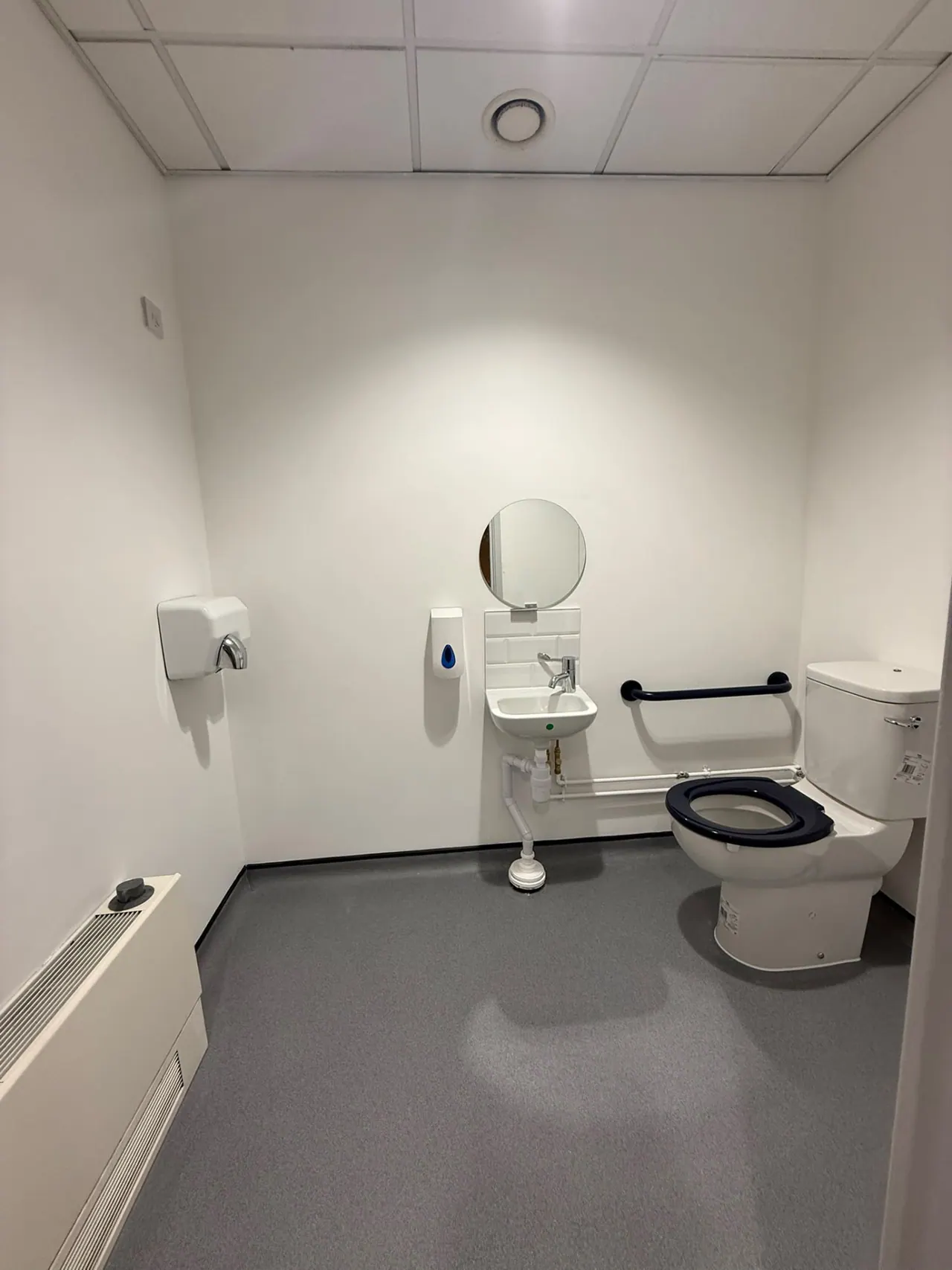 Refurbished commercial washroom with accessible toilet, grab rails and basins in Essex