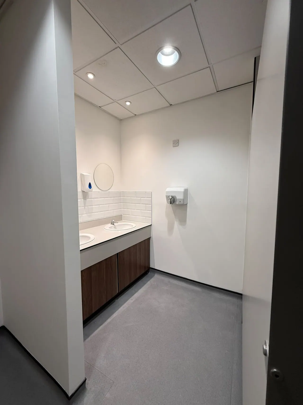 Refurbished commercial washroom with accessible toilet, grab rails and basins in Essex