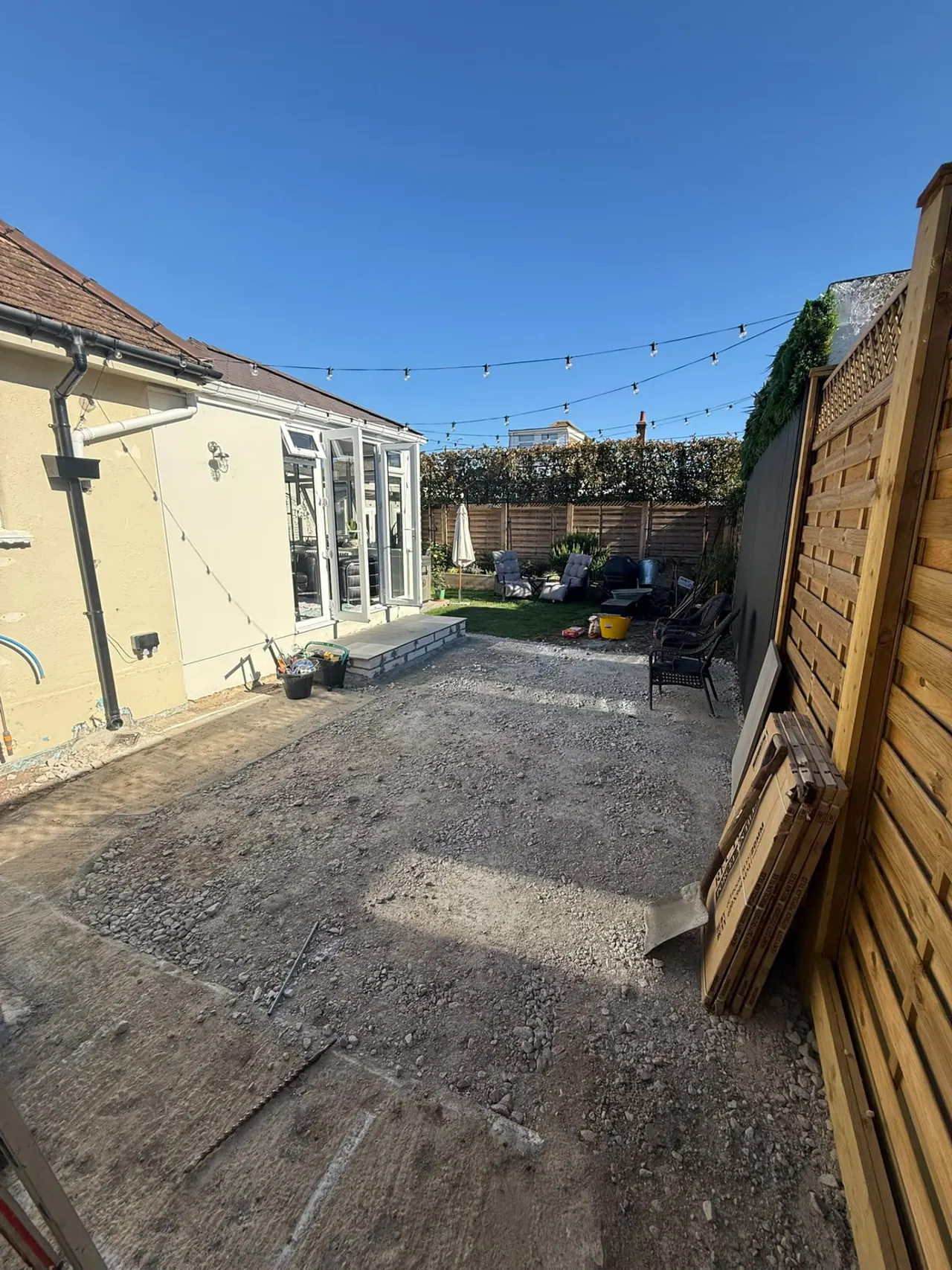 Garden before patio and fencing work, with old slabs and bare ground