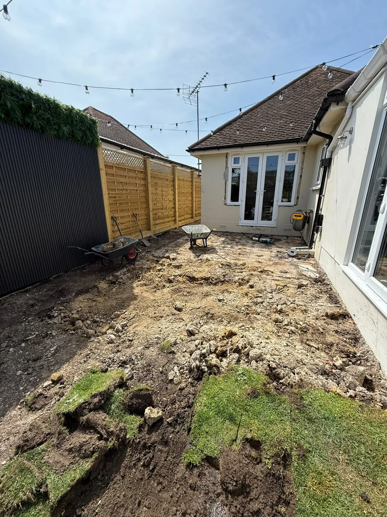 Garden before patio and fencing work, with old slabs and bare ground