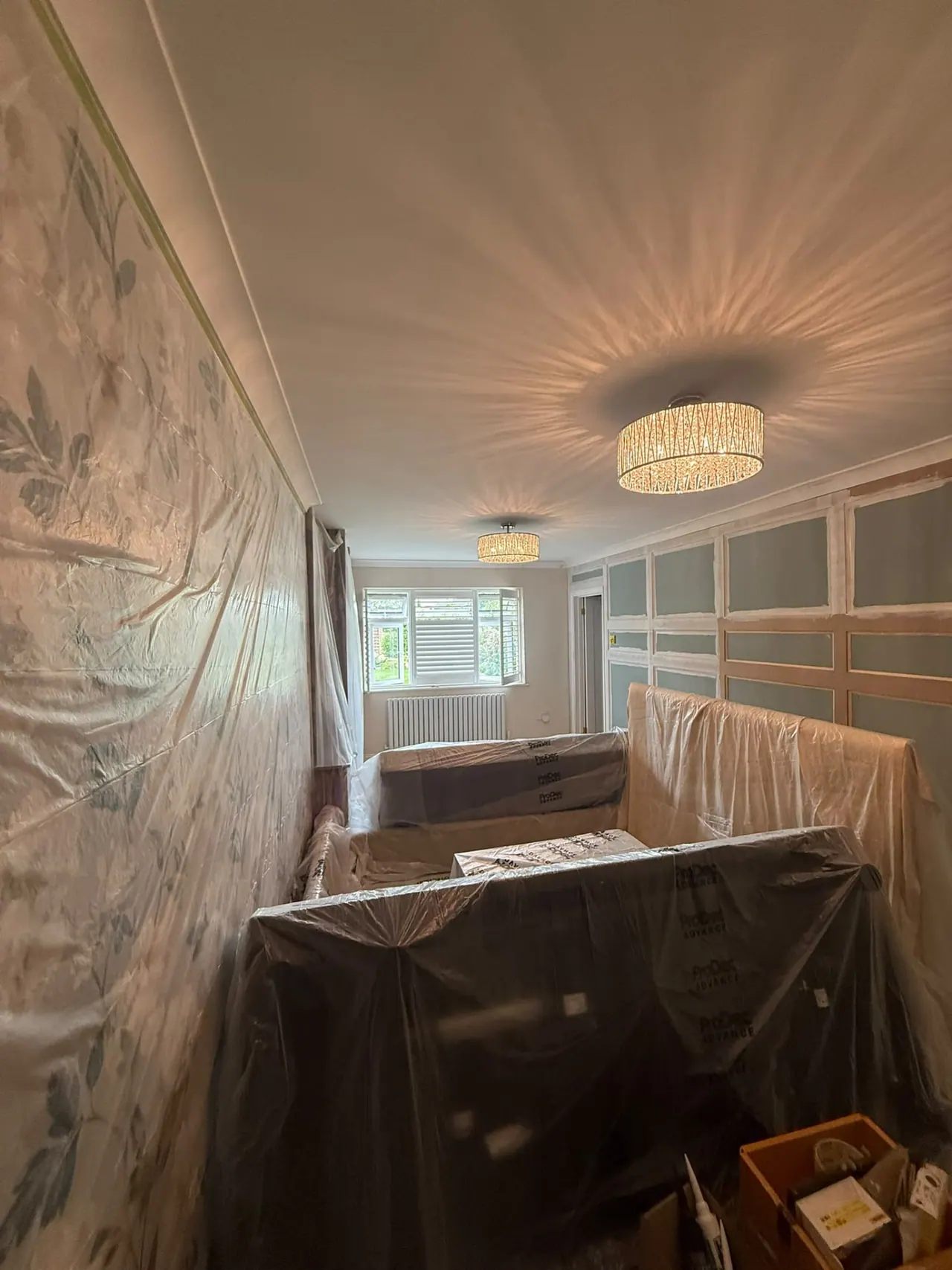 Room during painting and decorating preparation, furniture protected and panelling being fitted